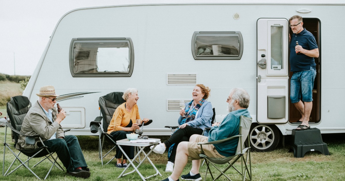 A group of friend enjoying a drink outside of their touring caravan while at a rally.